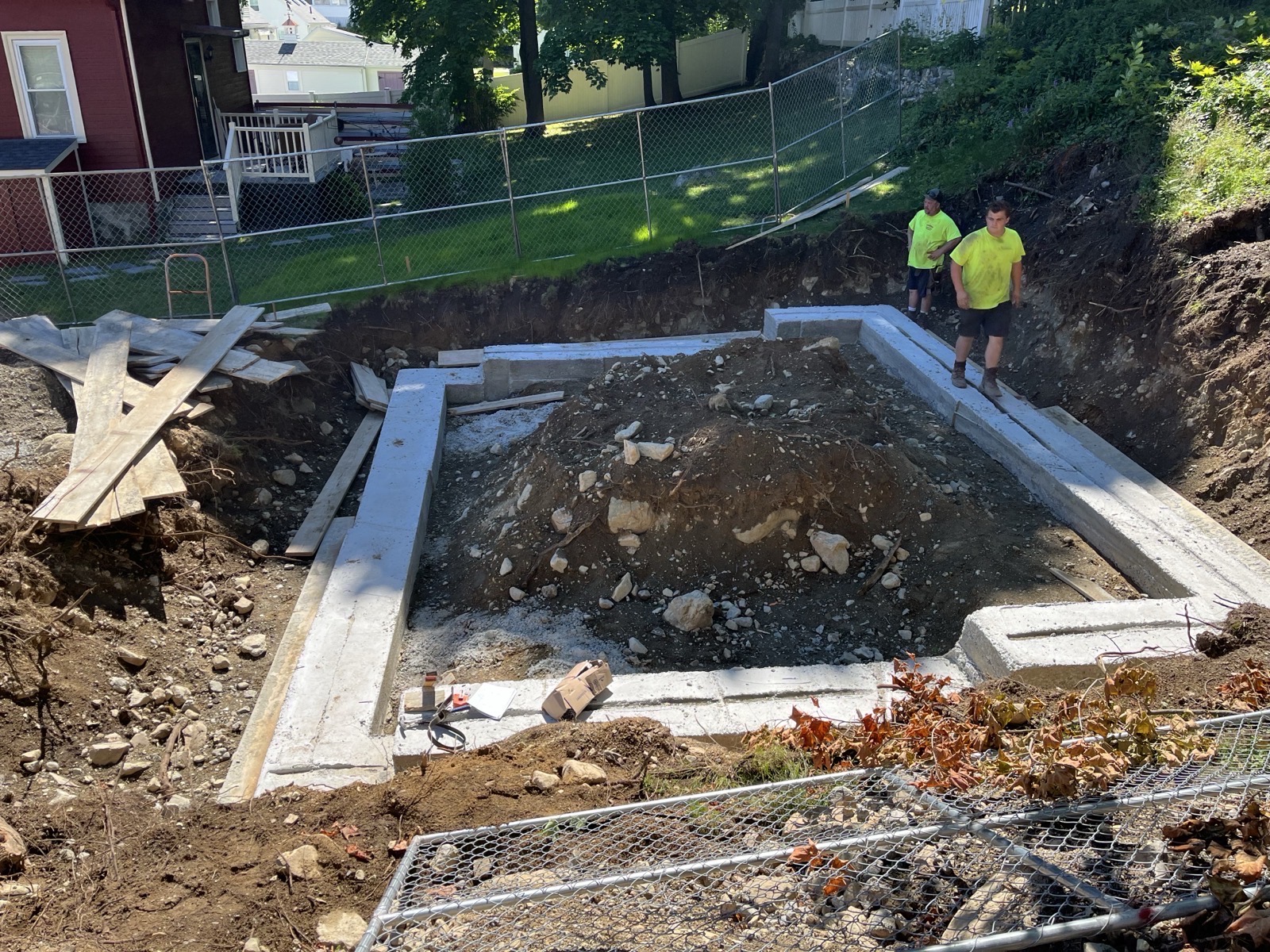 Cleared parcel and exposed foundation hole with crew on site