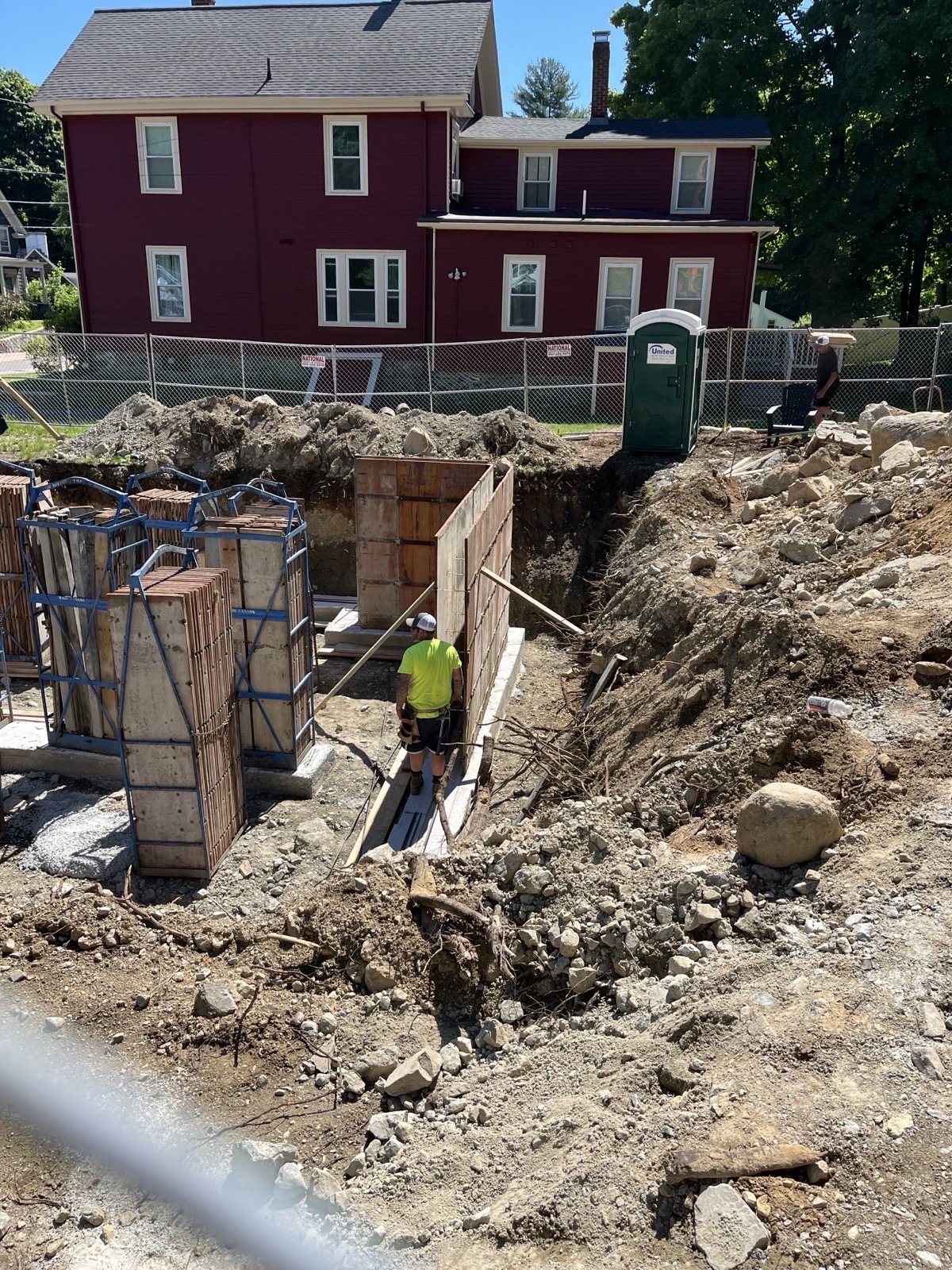 Excavated foundation pit with formwork and a crew member working
